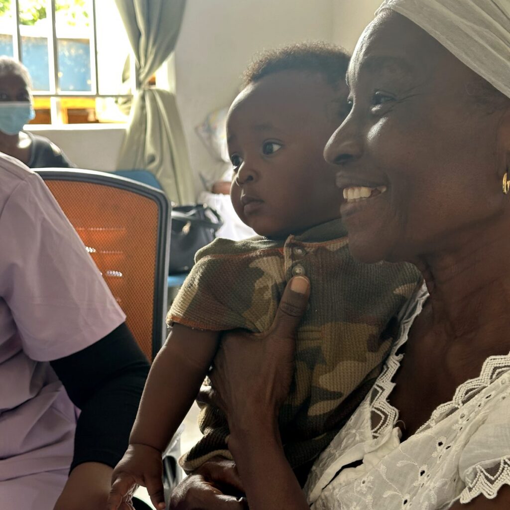 A grandmother smiles while holding a baby at a Pont clinic